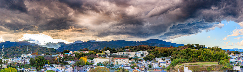 Odawara mountain range looking south. There is a storm forming above and the view is spectacular, Japanese houses can be seen in the foreground. 