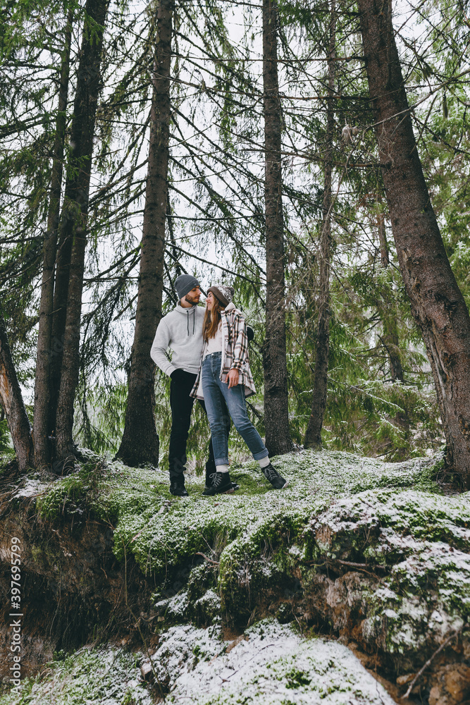 Couple among high fir trees in winter