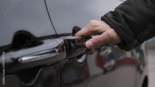 man in black jacket opens door of black minivan with his hand, press button and door slides to the side.