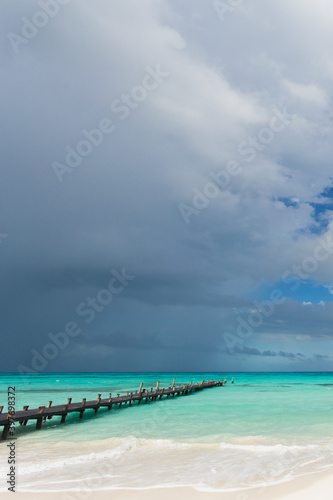 Old wooden pier on exotic white sand beach