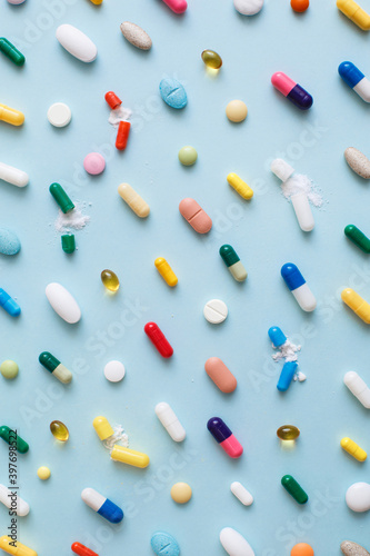 Creative layout of colorful pills and capsules on blue background. Minimal medical concept. Pharmaceutical, Covid-19 or Coronavirus. Flat lay, top view
