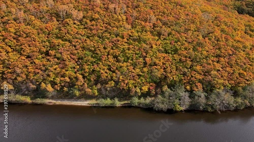 View from above. Panoramic shot of a beautiful shore with an autumn forest. the bank of a calm river. Colorful trees grow on a steep mountainside photo