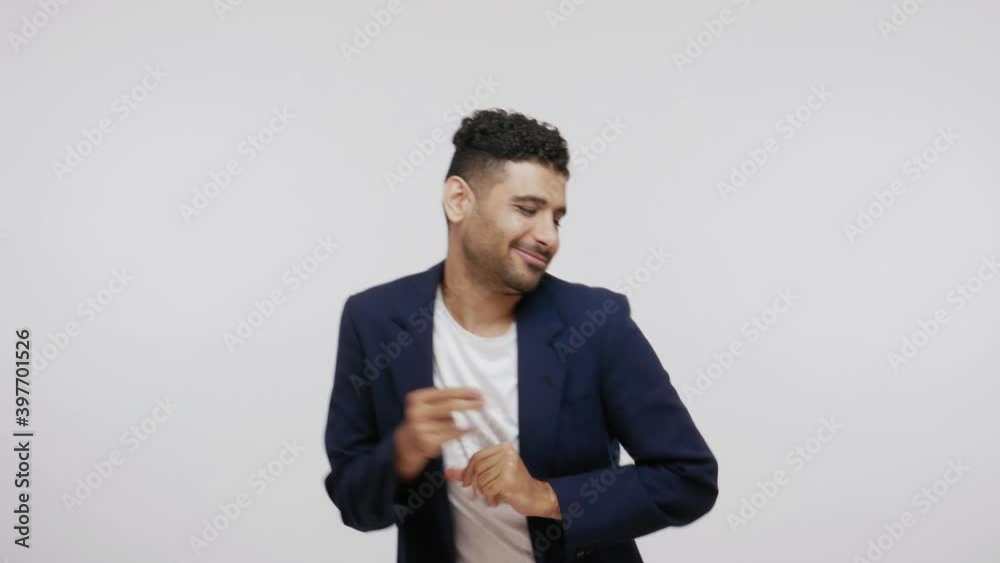 Positive bearded man in suit having fun dancing and moving to rhythm, dabbing raising hands, making dubdance gesture. Indoor studio shot isolated on gray background Positive bearded man in suit having fun dancing and moving to rhythm, dabbing raising hands, making dubdance gesture. Indoor studio shot isolated on gray background