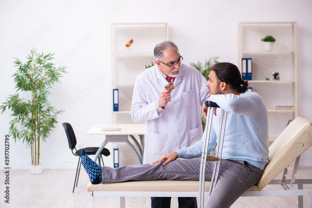 Obraz premium Young leg injured man visiting old doctor osteopath
