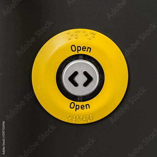 Generic yellow OPEN button on a train door shot straight on and close up.