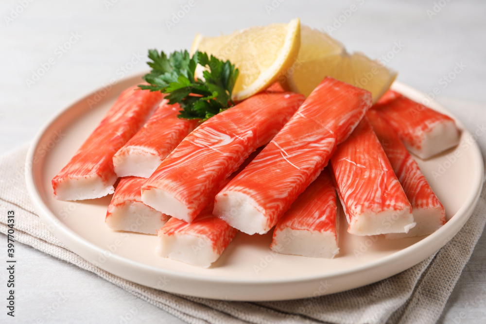 Plate of fresh crab sticks with lemon on white table, closeup Plate of fresh crab sticks with lemon on white table, closeup