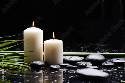 spa still life of with candle  and zen black stones  and green palm wet on background 