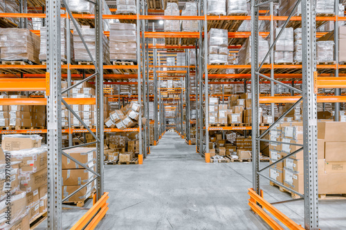 Large warehouse. Tall and long metal racks filled with various boxes, containers and drawers