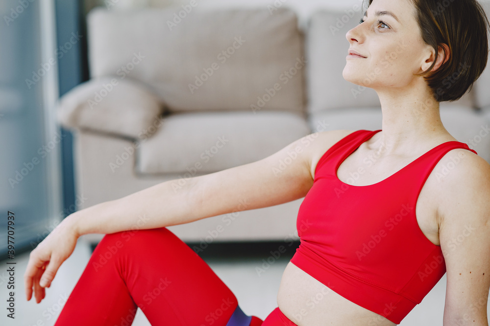 Girl at home. Woman make yoga. Lady in a red sports uniform.
