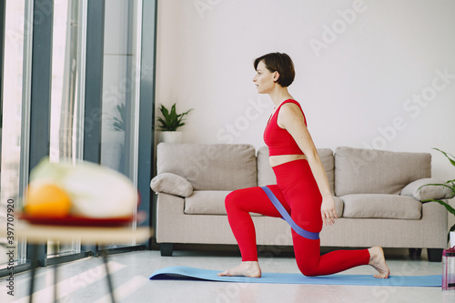 Girl at home. Woman make yoga. Lady in a red sports uniform.