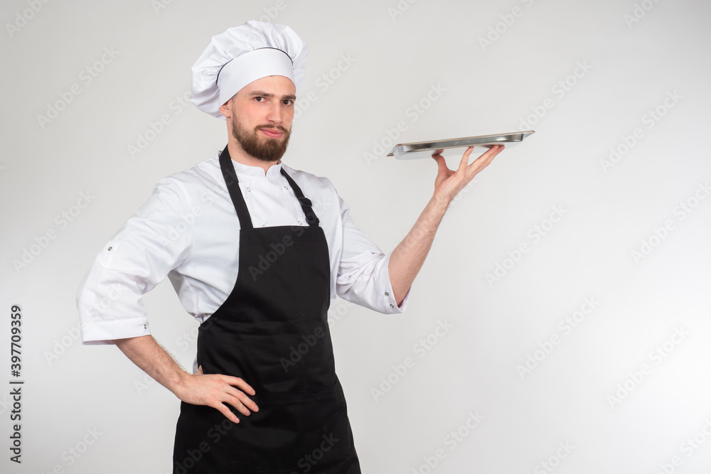 Chef cook holding an empty tray on gray background. Cook is posing with empty tray. Serving dishes in a restaurant. Concept - career of a chef. Work in restaurant business. Baker. Work confectioner Chef cook holding an empty tray on gray background. Cook is posing with empty tray. Serving dishes in a restaurant. Concept - career of a chef. Work in restaurant business. Baker. Work confectioner