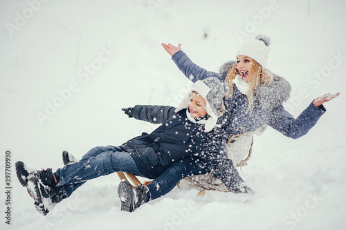 Beautiful mother in a blue jacket. Family sledding in a winter park. Little boy in a cute hat