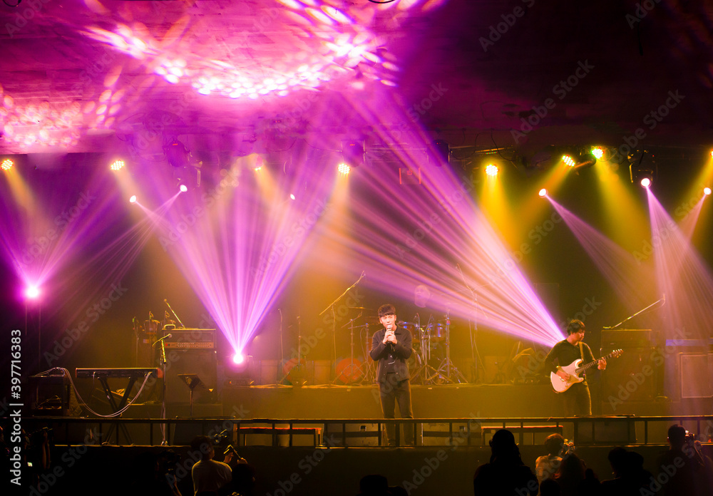 High performance singer on stage in concert lighting on stage, Concert stage with lights and musical instruments during rock concert. Lights rays in dark on stage. Performance on stage