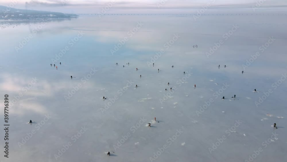 Nice top view. Many people fish on the thin ice of the Amur Bay in Vladivostok. The camera pans over a multitude of winter fishermen sitting on thin ice. Nice top view. Many people fish on the thin ice of the Amur Bay in Vladivostok. The camera pans over a multitude of winter fishermen sitting on thin ice.
