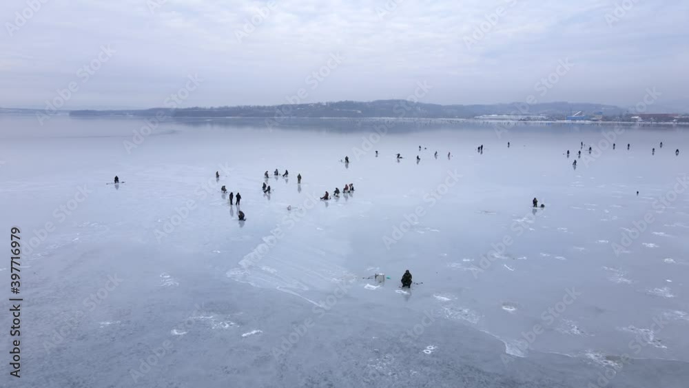 View from above. Fishermen sit on thin ice in the water area of the Amur Bay in Vladivostok. Winter fishing in Russia. Nice flat ice. View from above. Fishermen sit on thin ice in the water area of the Amur Bay in Vladivostok. Winter fishing in Russia. Nice flat ice.