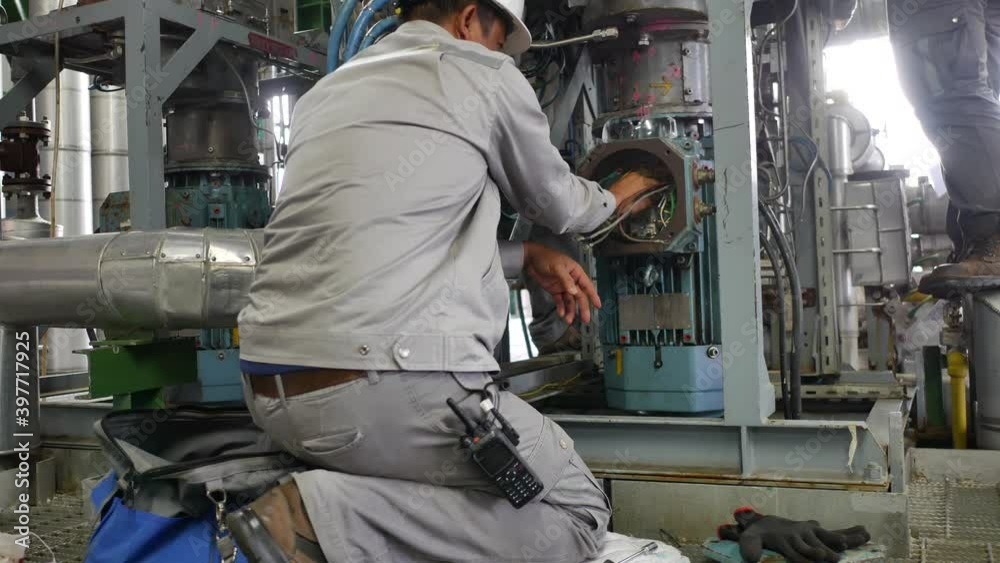 An electrician is disconnecting the wires from the electric motor in preparation for the maintenance of the industrial machinery. An electrician is disconnecting the wires from the electric motor in preparation for the maintenance of the industrial machinery.
