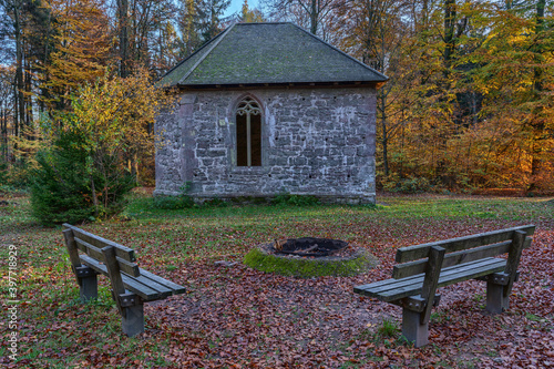 Small church in the woods with a fireplace and two benches