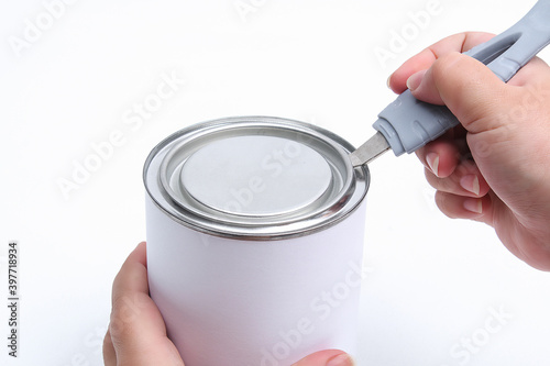 Foto A man opens a jar of white paint with a can opener on a white background