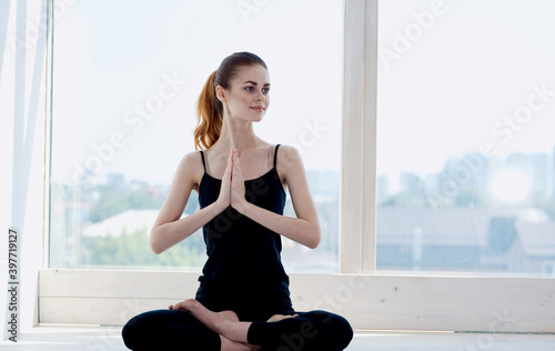 Woman practices yoga indoors near the window meditation relax crossed legs