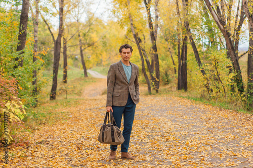 Tall handsome man with a bag on the autumn alley © Smile