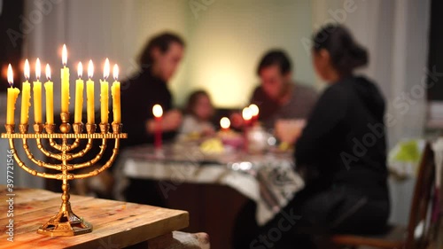 Hanukkah is a Jewish holiday that lasts eight days. Happy Jewish family, mom, dad and children have dinner together at home at the holiday table. Menorah lighting photo