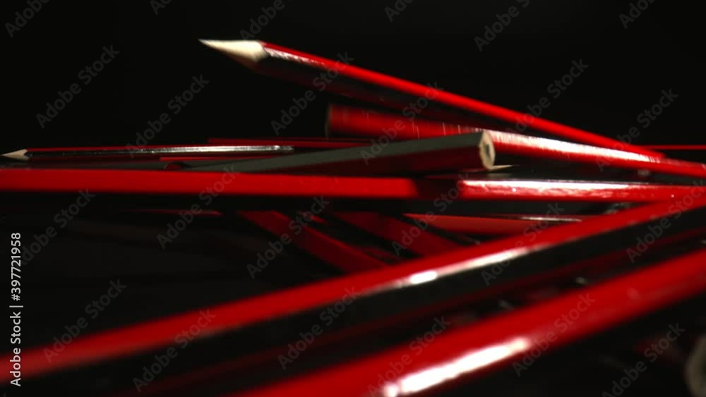 Packaging of Pencils with red and black stripes falling on a black surface. Art school concept. High quality Packaging of Pencils with red and black stripes falling on a black surface. Art school concept. High quality