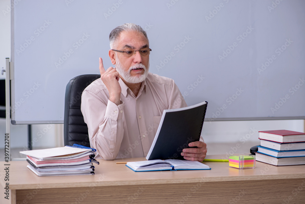 Old male teacher sitting in the classroom Old male teacher sitting in the classroom