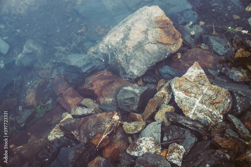 Nature background with many stones on bottom of mountain lake with clear water. Natural texture of stony lake bottom. Full frame of stone pile closeup in calm water. Rocks in transparent water.