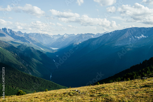 Awesome vivid view to great mountains, glacier and green forest valley with alpine lake and river. Beautiful alpine landscape of vast expanses. Wonderful colorful highland scenery with giant mountains