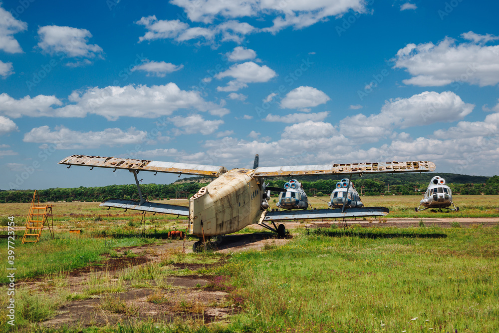 Abandoned, destroyed planes stand on the grass under blue sky with white clouds. Abandoned, destroyed planes stand on the grass under blue sky with white clouds.