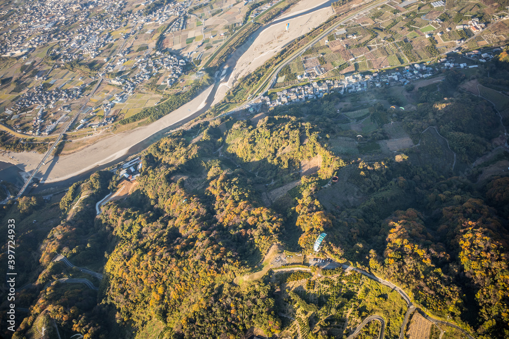 寺山スカイスポーツ周辺の紅葉の中を飛ぶパラグライダー。和歌山県紀の川市