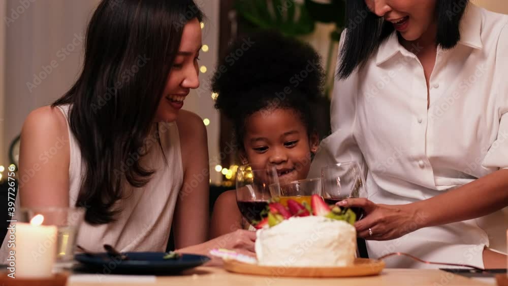 Happy little girl celebrating her birthday with Lgbt family blowing out the candles on her cake.Lesbian party birthday. slow motion. Happy little girl celebrating her birthday with Lgbt family blowing out the candles on her cake.Lesbian party birthday. slow motion.