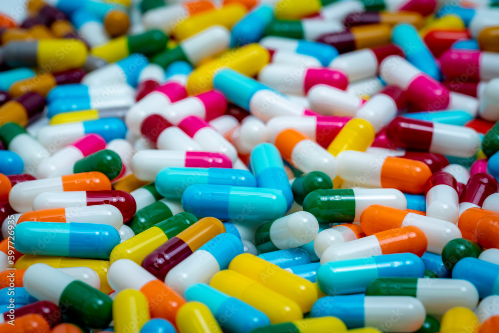 Selective focus on multi-colored antibiotic capsule pills. Antibiotic drug resistance concept. Pile of colorful capsule pills. Pharmaceutical industry. Antimicrobial drug for treatment infection. Selective focus on multi-colored antibiotic capsule pills. Antibiotic drug resistance concept. Pile of colorful capsule pills. Pharmaceutical industry. Antimicrobial drug for treatment infection.