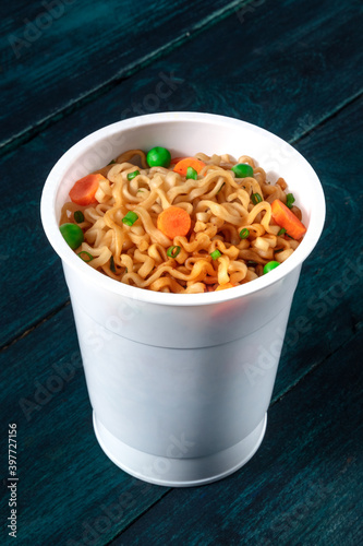 Ramen cup. Instant noodles in a plastic cup, close-up on a wooden background