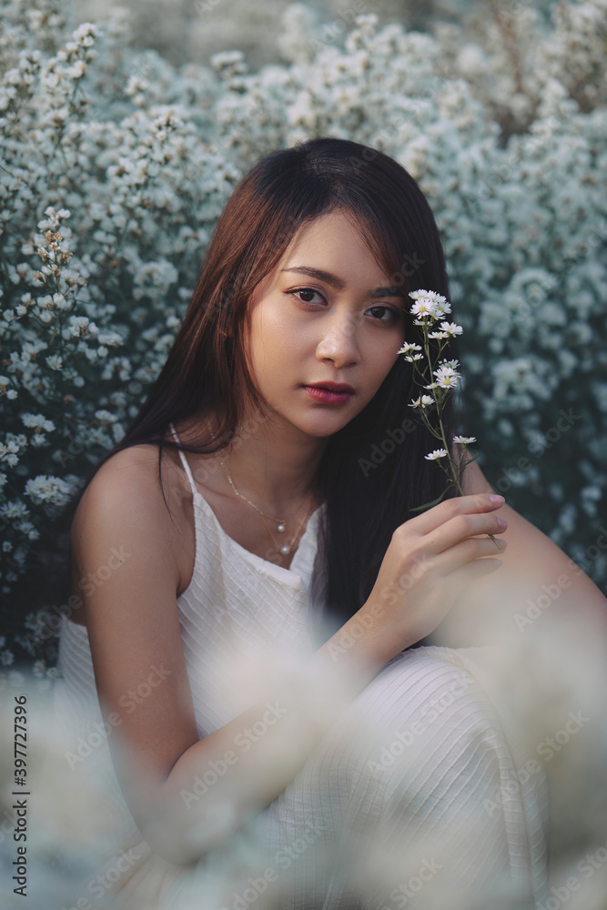 Asian woman in white dress sitting in the garden of white flowers
