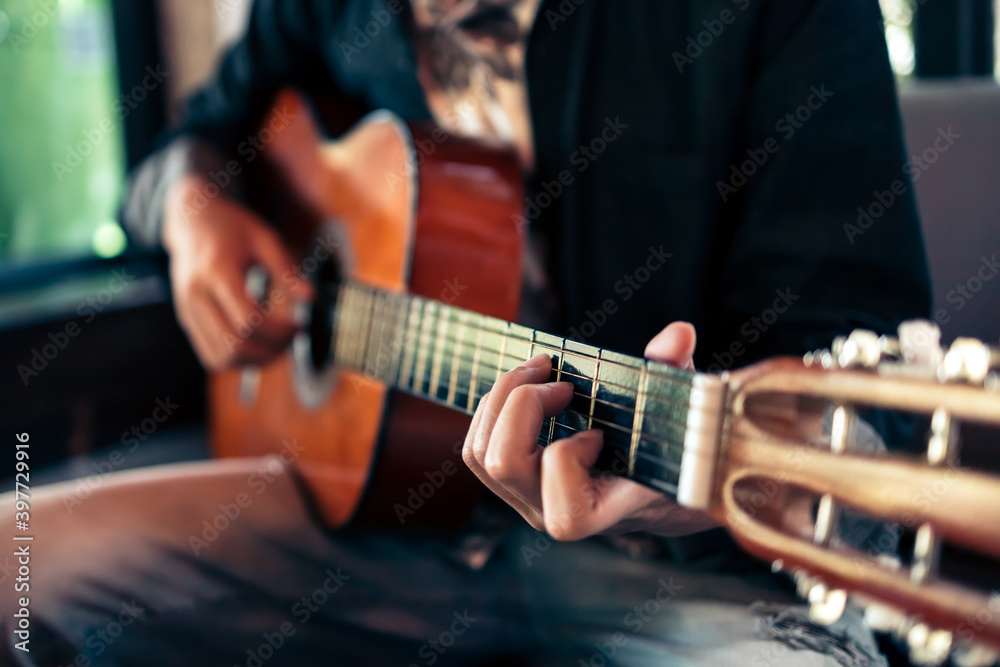 man's hands playing acoustic guitar.