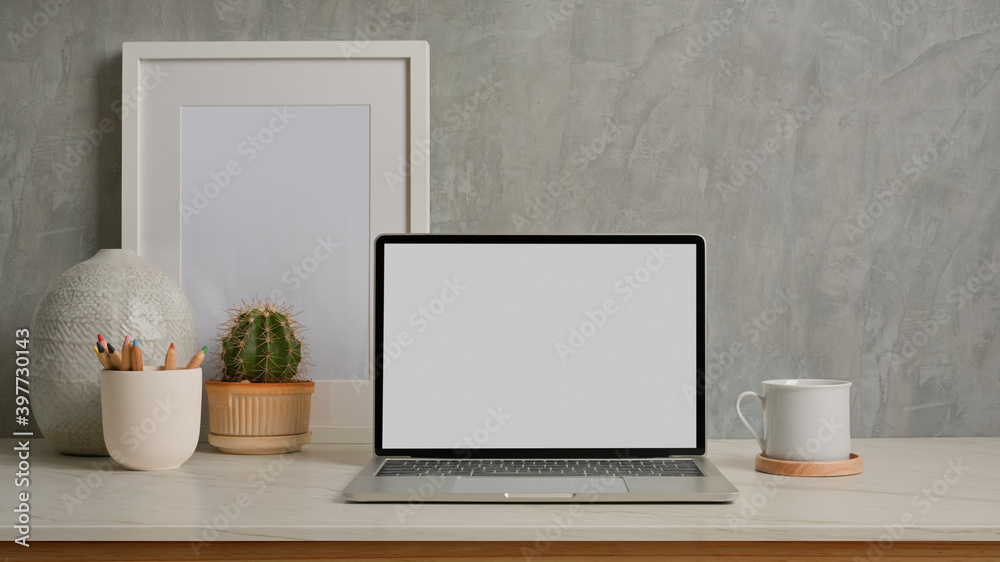 Close up view of home office desk with laptop, mock up frame and decorations Close up view of home office desk with laptop, mock up frame and decorations