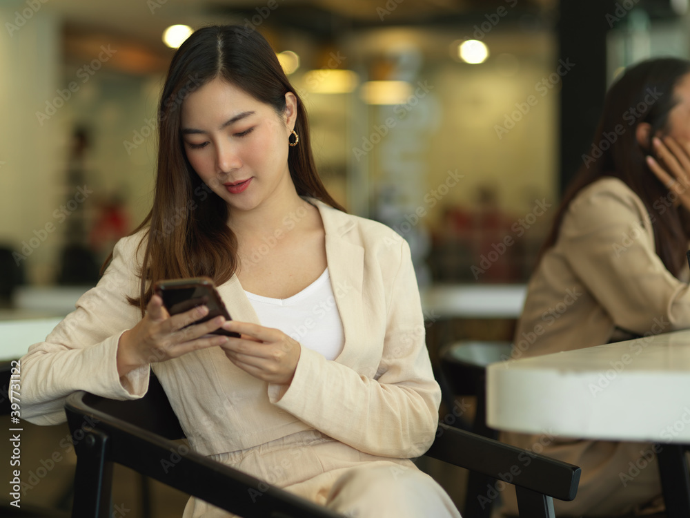 Portrait of businesswoman using smartphone while relaxed sitting in meeting room