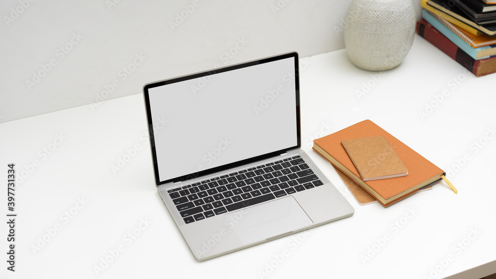 Top view of worktable with laptop, notebook, books and vase on white table Top view of worktable with laptop, notebook, books and vase on white table