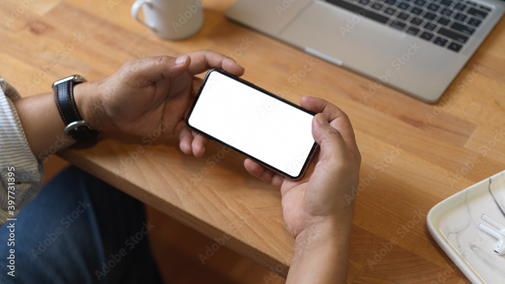Close up view of male hands using horizontal smartphone on wooden worktable Close up view of male hands using horizontal smartphone on wooden worktable