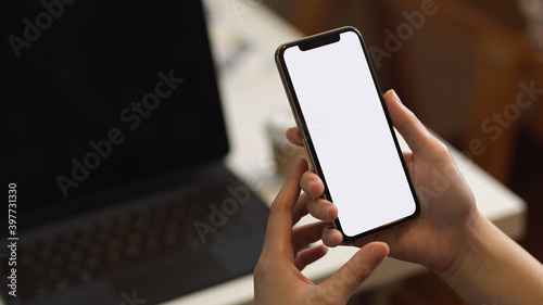 Close up view of female holding smartphone in blurred office room background