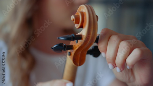 Teenage girl hands tuning violin. Young woman checking pegs of violin