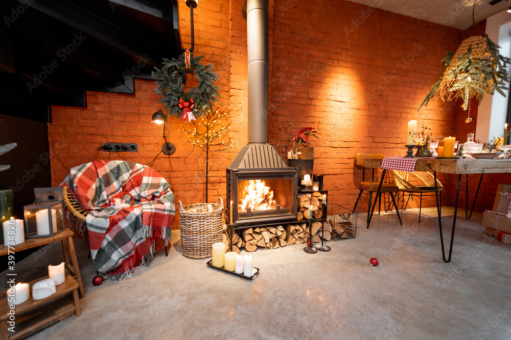 Naklejka premium Fireplace area of a beautiful loft-style interior with real brick and concrete floors decorated for the New Year holidays. The concept of home comfort