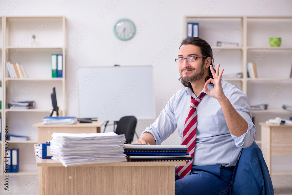 Young male employee being positive in spite of excessive work Young male employee being positive in spite of excessive work