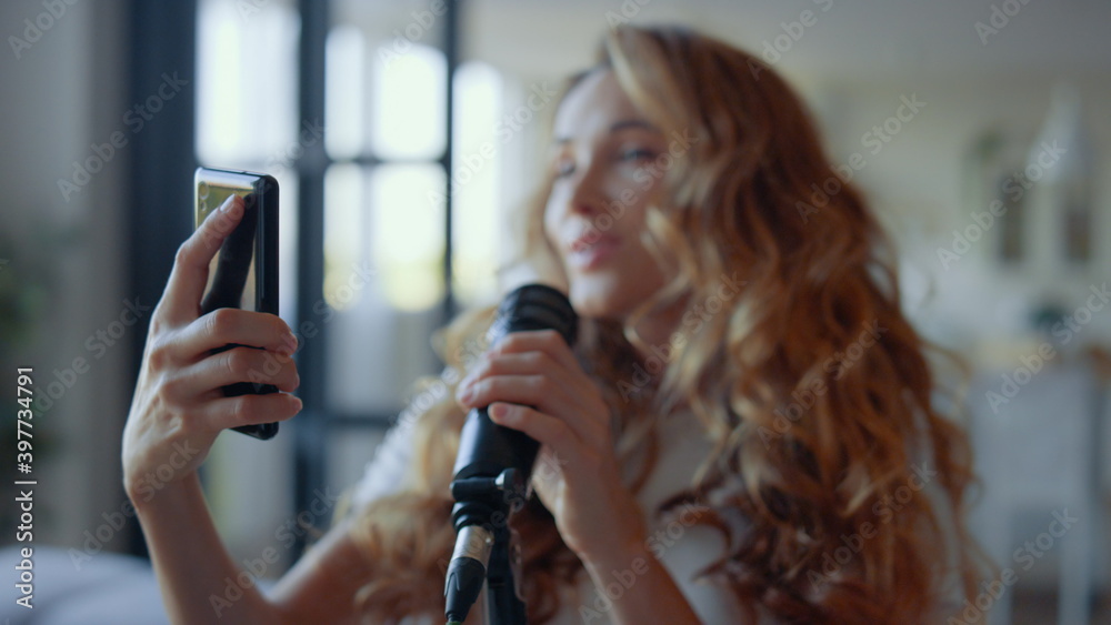Woman performing song in microphone. Vocalist looking text of song on smartphone Woman performing song in microphone. Vocalist looking text of song on smartphone