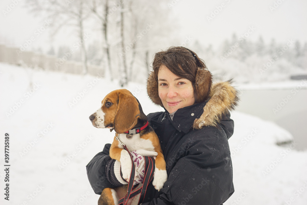 beautiful girl with short hair is walking on a warm winter day with her pet beagle puppy