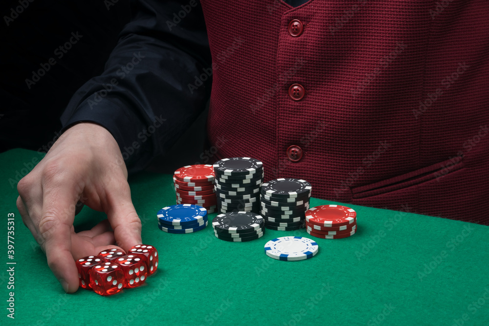 the croupier picks up the winning chips from the green poker table