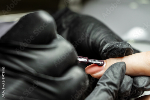 The manicure master applies a nail Polish to the client's nails in a beauty salon. drawing on the client's nails. Close up.
