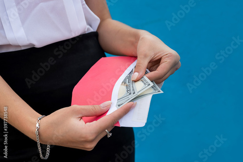 female hands in handcuffs holding an envelope with dollars