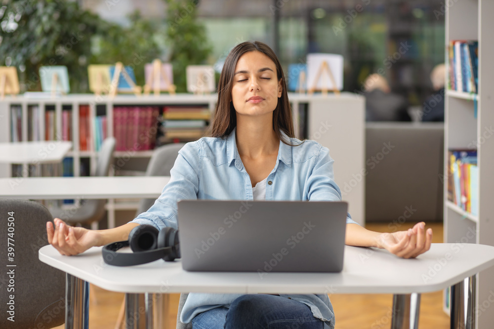 Beautiful happy young woman or student female meditates at the workplace Beautiful happy young woman or student female meditates at the workplace